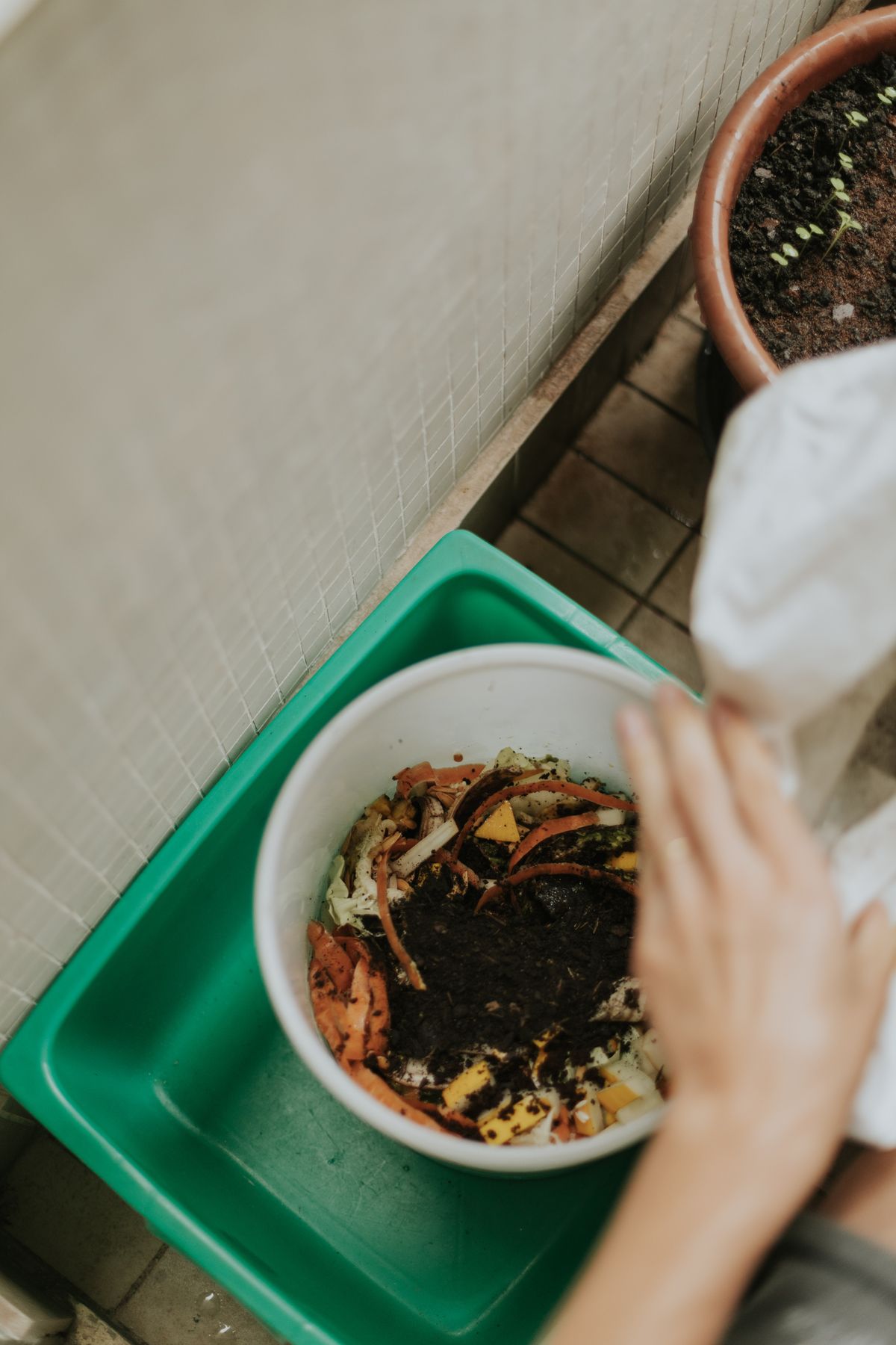 Economía circular: qué es, principios y ejemplos 6 Manos añadiendo restos orgánicos al compost casero